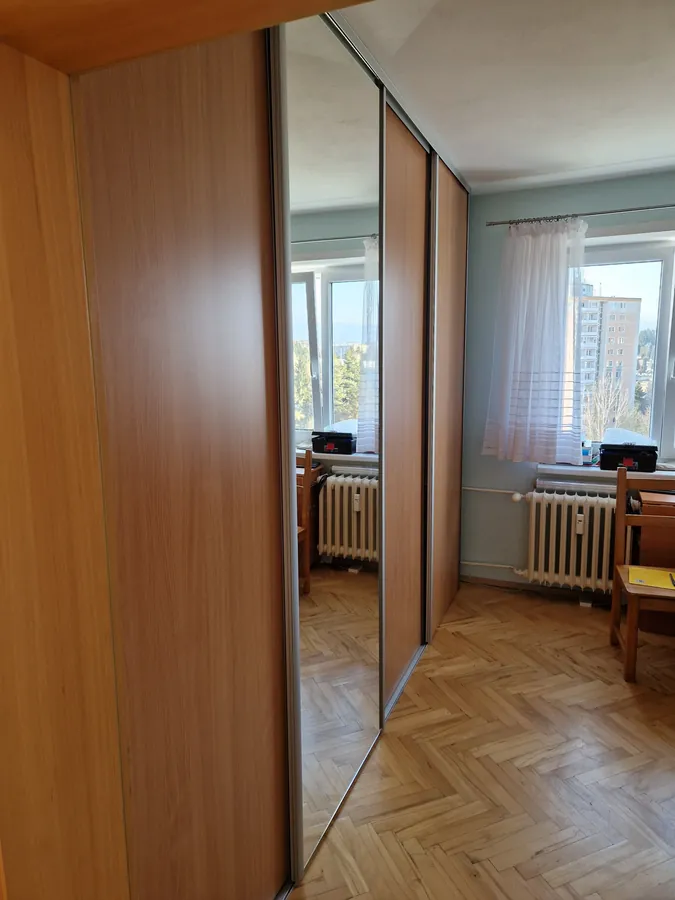 Vstavaná skriňa s posuvnými dverami, striedajú sa panely v drevodekore a zrkadlo